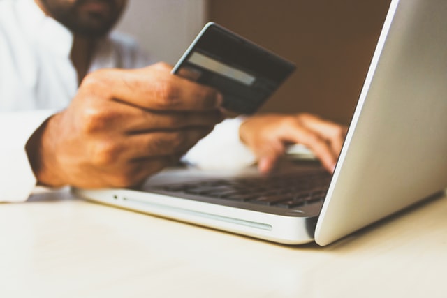 Landlord 101: Property management fees explained | HomeVault man with credit card wanting to pay using a laptop